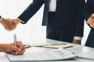 Two business executive shake hand in boardroom, sealing agreement merging two company. Handshake symbolize business partnership and cooperation. Corporate acquisition and merger concept. Shrewd