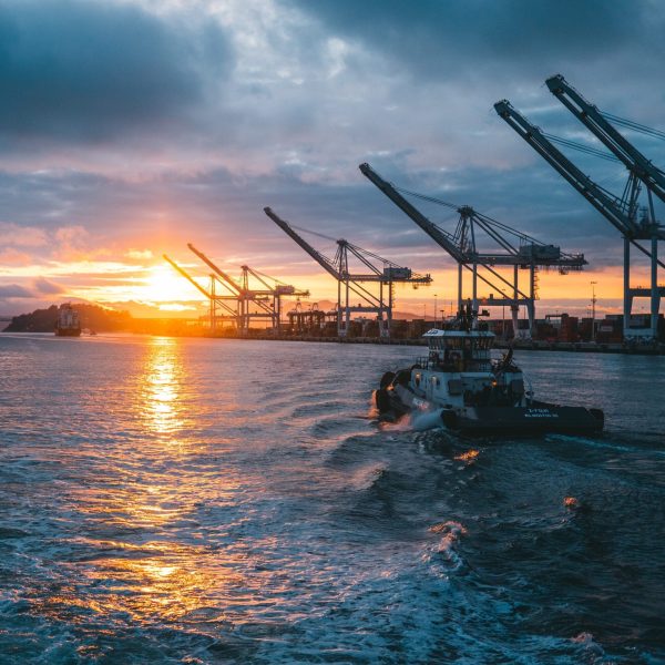 a panoramic shot of oil rigs at sea with a beautiful sunset in the background, under cloudy sky